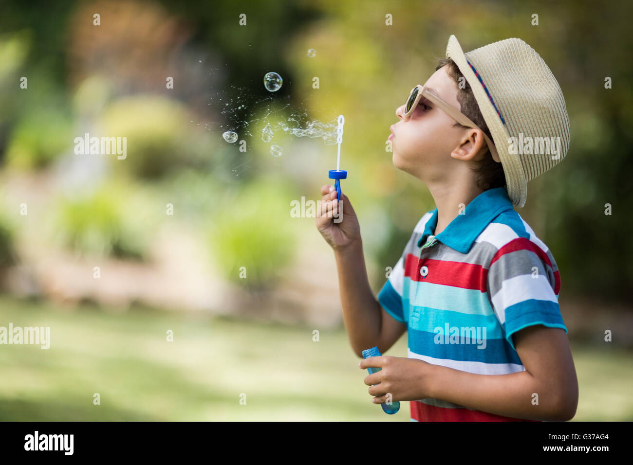 Young boy in sunglasses blowing bubbles through bubble wand Stock Photo