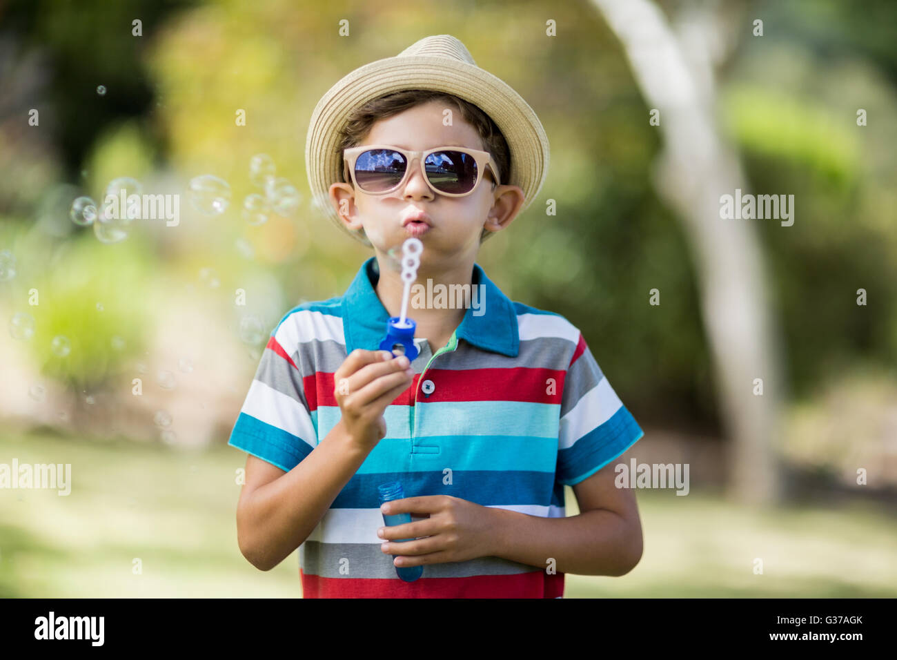 Young boy in sunglasses blowing bubbles through bubble wand Stock Photo
