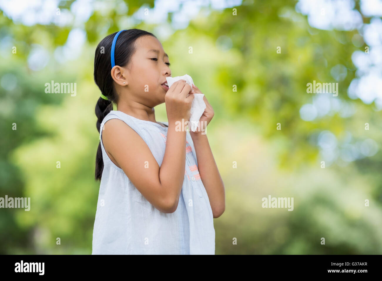 Girl blowing her nose with handkerchief while sneezing Stock Photo