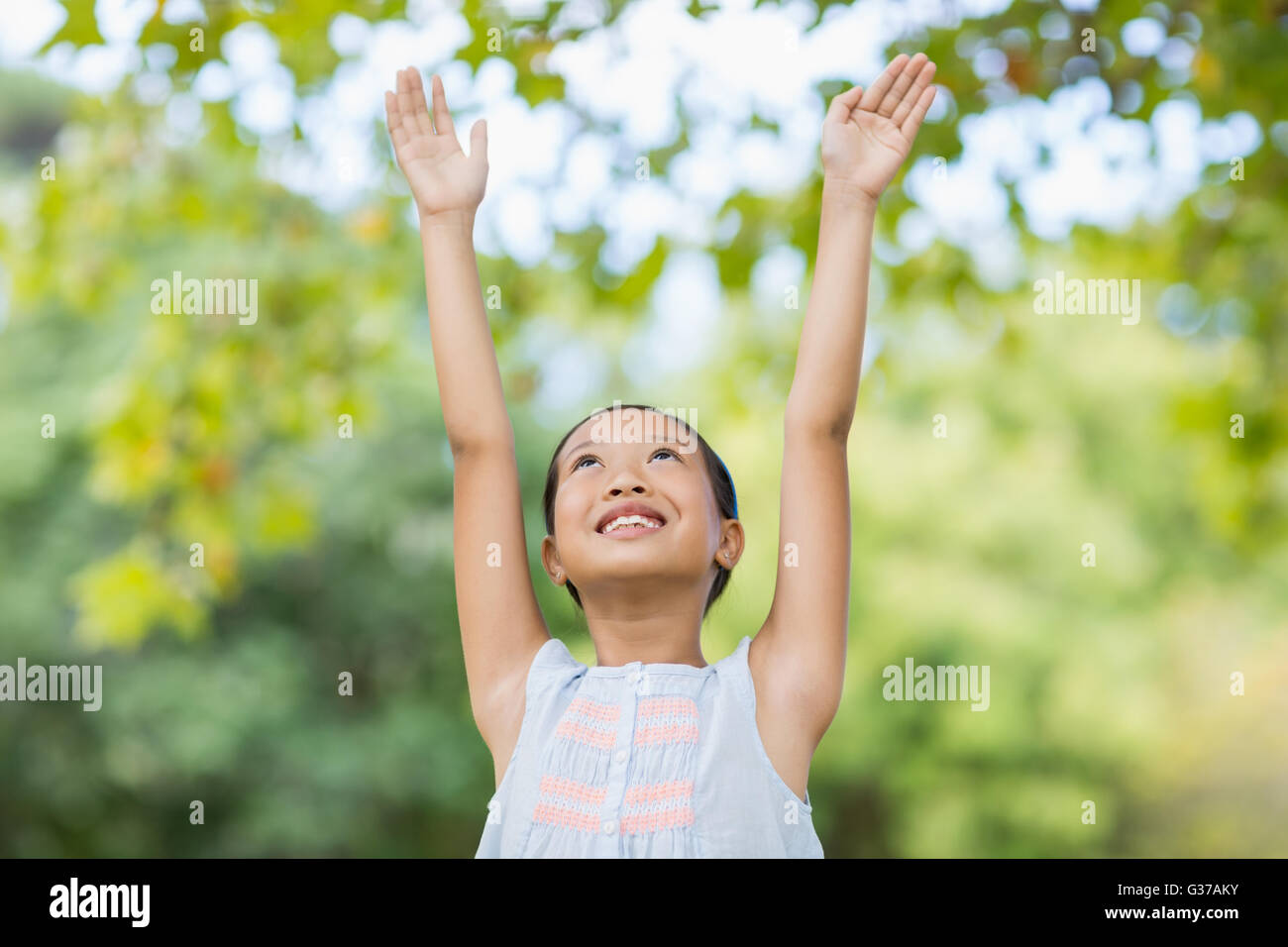 Smiling girl standing with arms raised Stock Photo