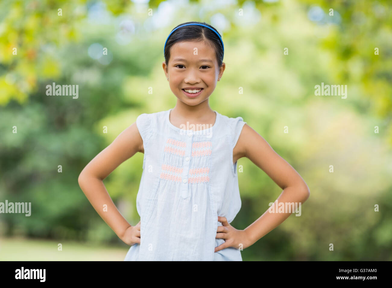 Portrait of smiling girl standing with hand on hip Stock Photo - Alamy