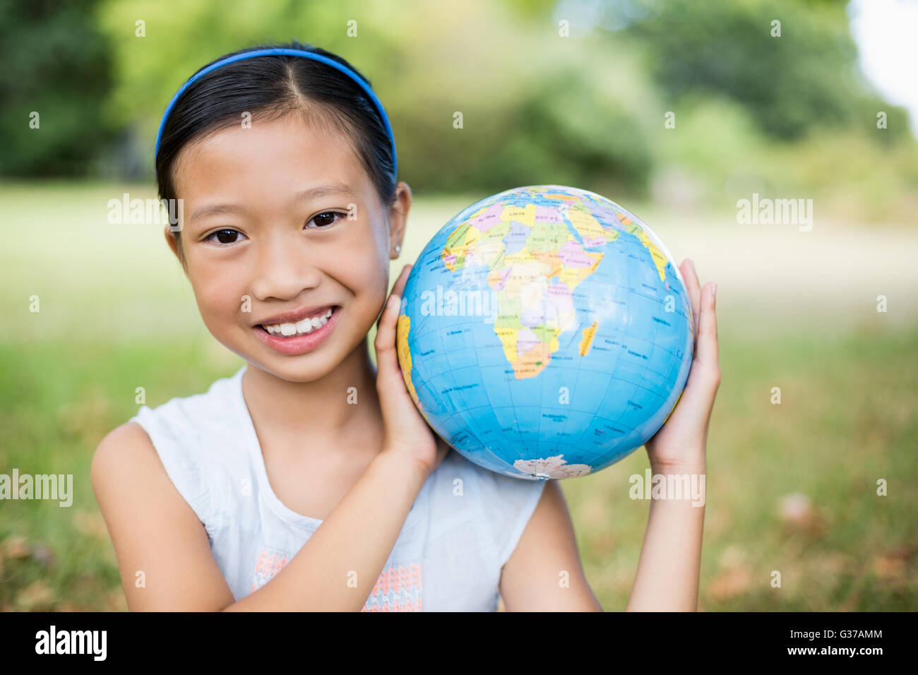 Portrait of smiling girl carrying a globe on her shoulder Stock Photo