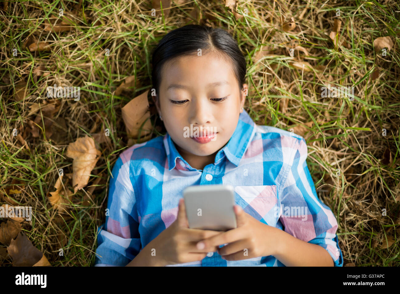 Girl lying on grass and using mobile phone Stock Photo - Alamy