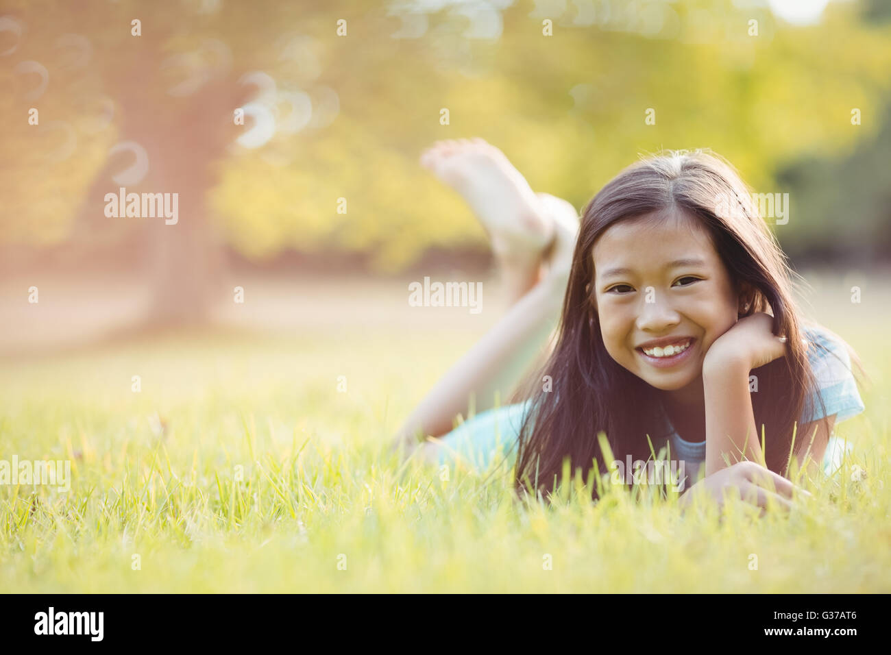 Smiling young girl lying on grass Stock Photo - Alamy