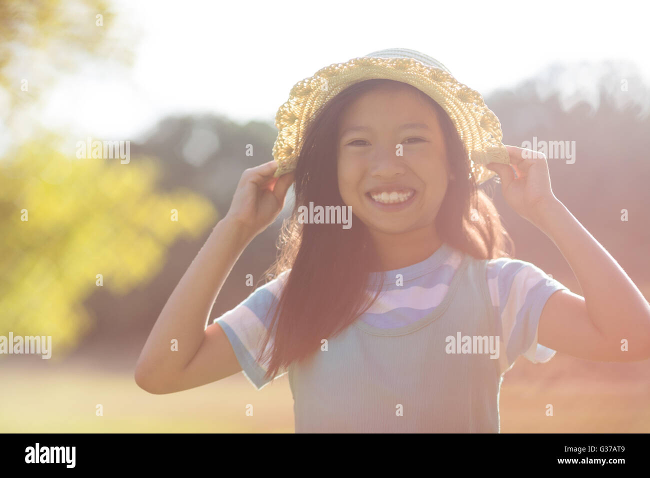 Portrait of young girl wearing hat smiling in park Stock Photo - Alamy