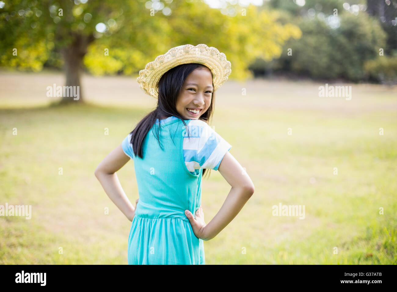 Portrait of smiling girl standing with hand on hip in park Stock Photo ...