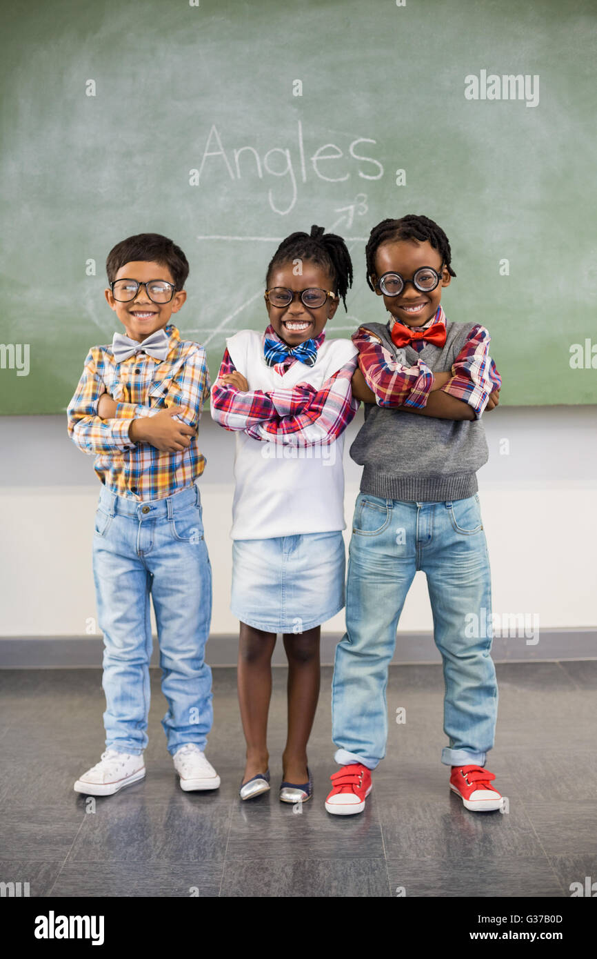 Portrait of three school kids standing with arms crossed against chalkboard Stock Photo