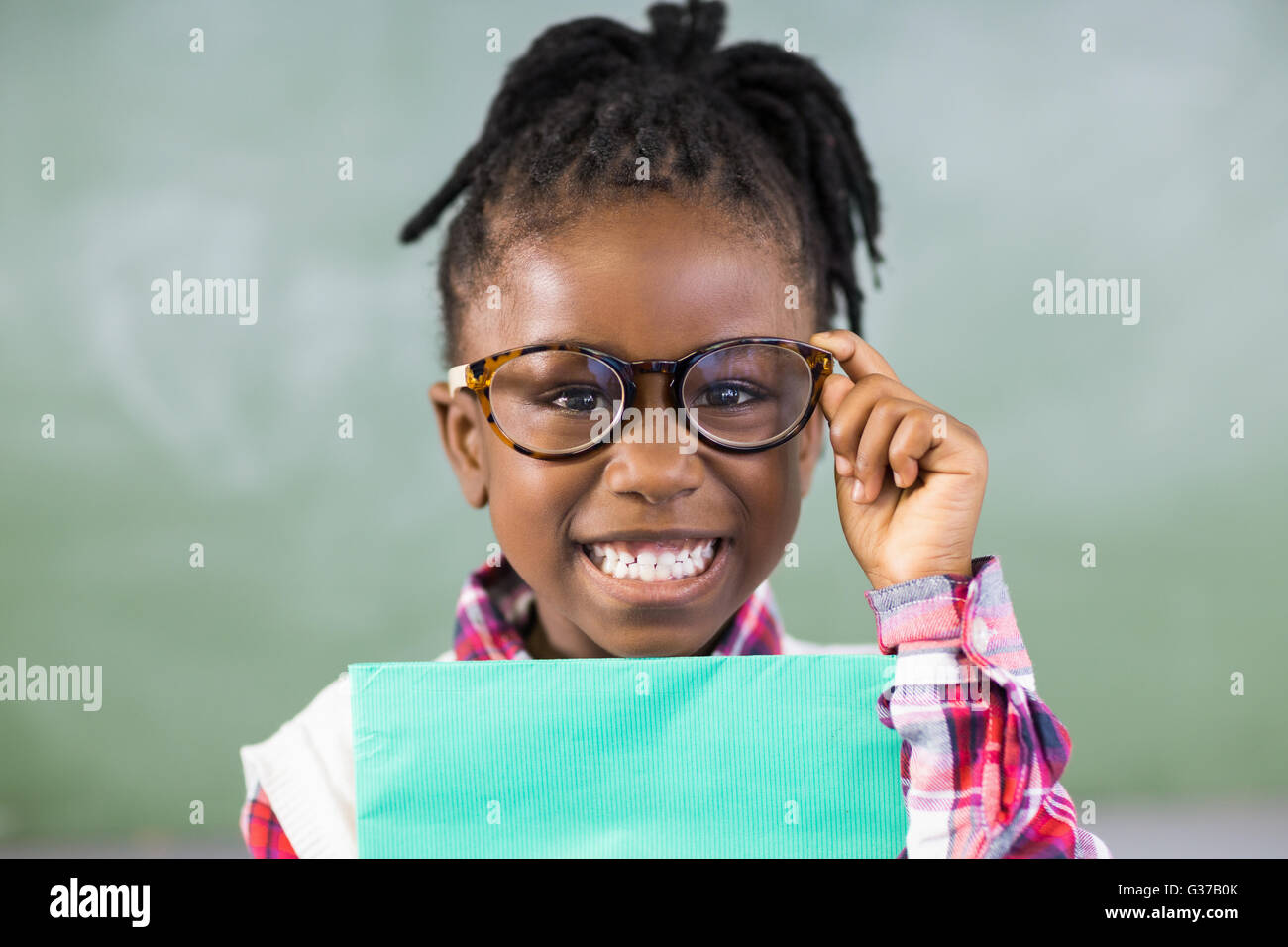 Portrait of happy schoolgirl holding file in classroom Stock Photo - Alamy