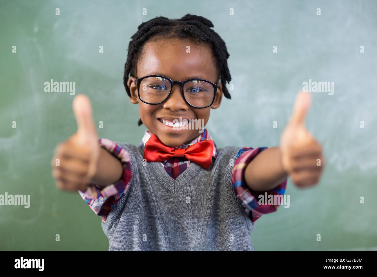 Portrait of smiling schoolboy showing thumbs up in classroom Stock ...