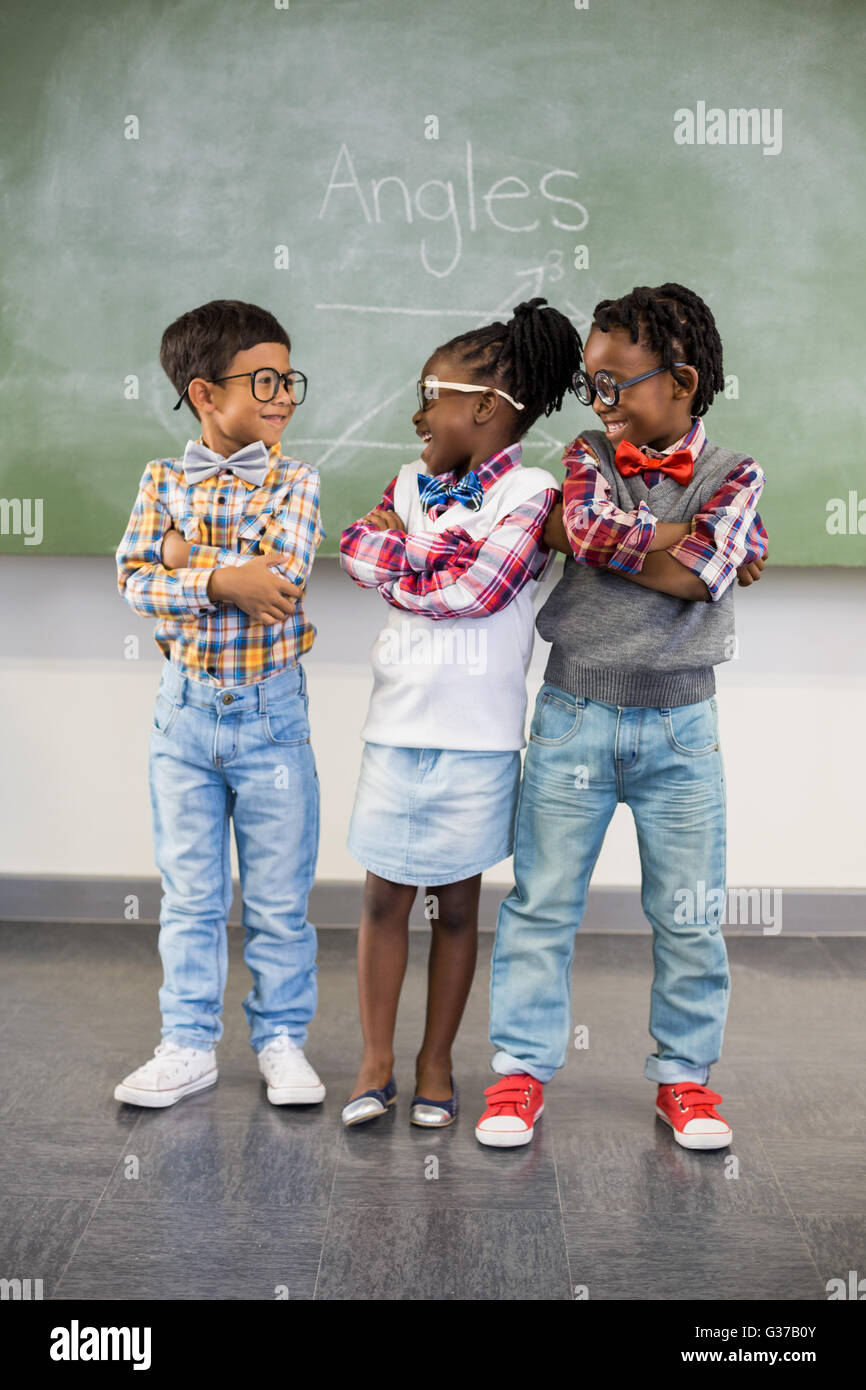 Three school kids talking to each other in classroom Stock Photo