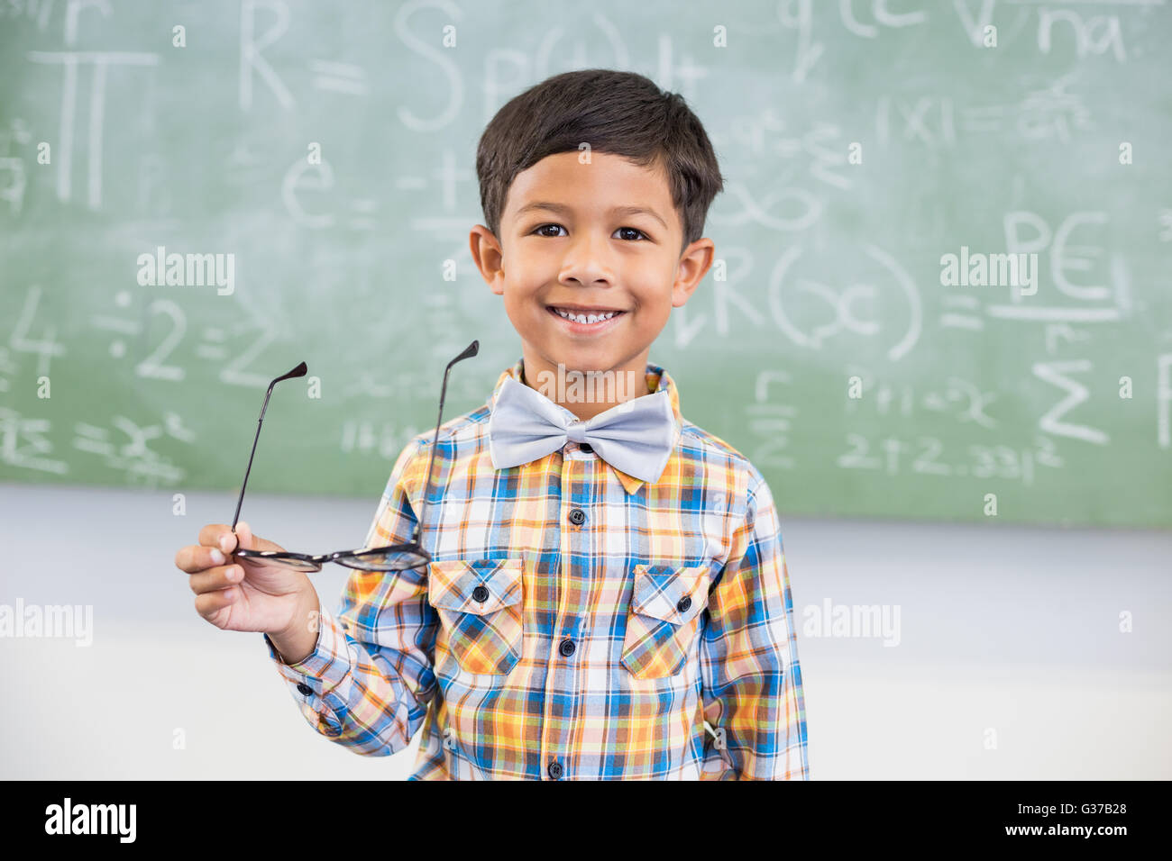 Portrait of schoolboy smiling against chalkboard in classroom Stock ...