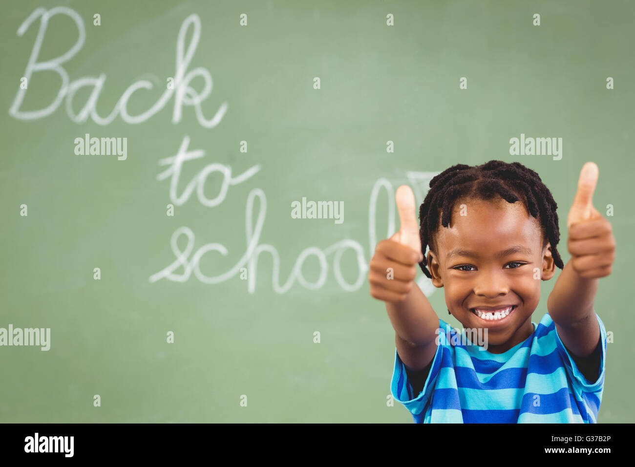 Portrait of smiling schoolboy showing thumbs up in classroom Stock ...