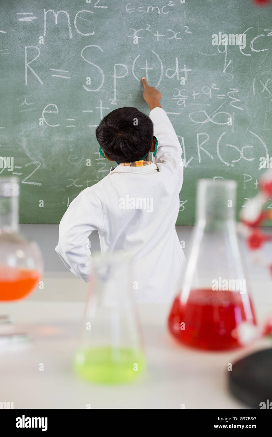 Schoolboy solving mathematics on chalkboard in classroom Stock Photo