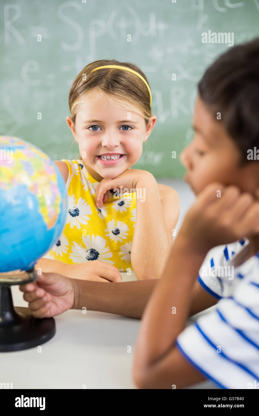 Happy school kids with globe in classroom Stock Photo