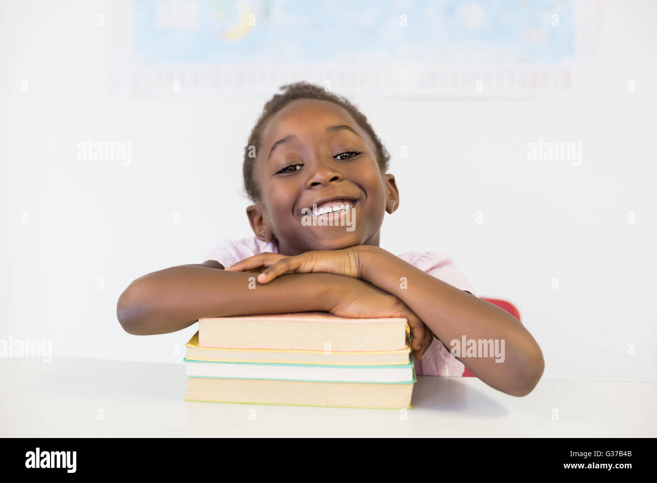 Portrait of smiling girl with books in classroom Stock Photo - Alamy