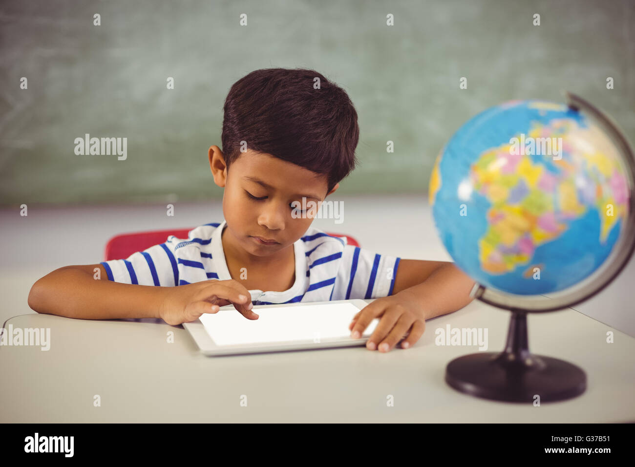 Schoolboy using digital tablet in classroom Stock Photo - Alamy