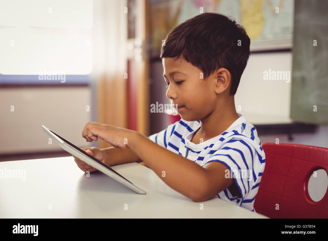 Schoolboy using digital tablet in classroom Stock Photo - Alamy