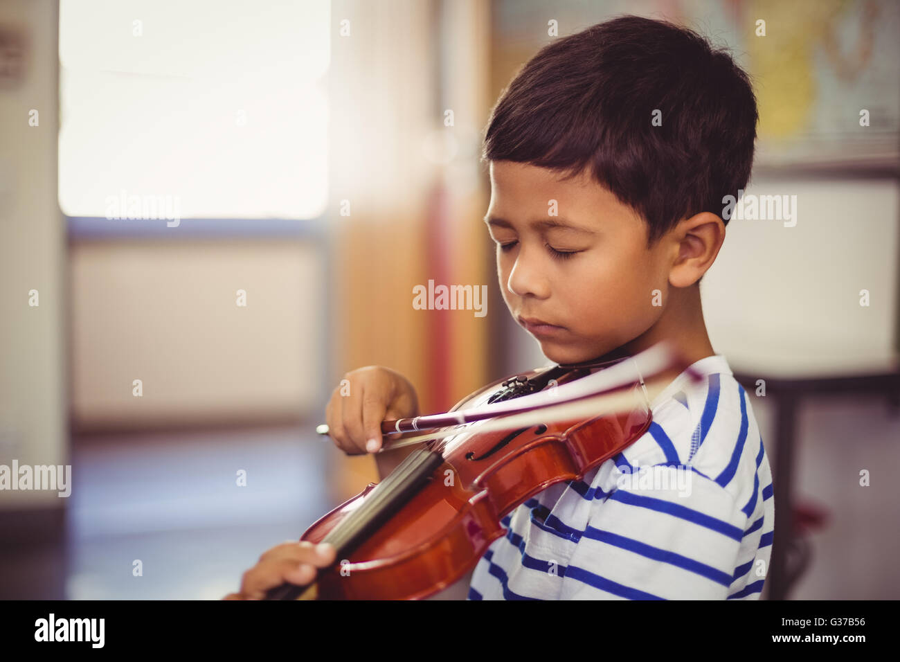 Schoolboy playing violin in classroom Stock Photo