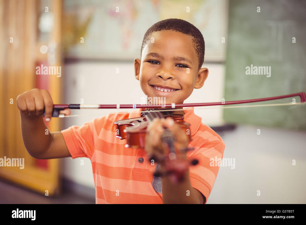 Portrait of smiling schoolboy playing violin in classroom Stock Photo