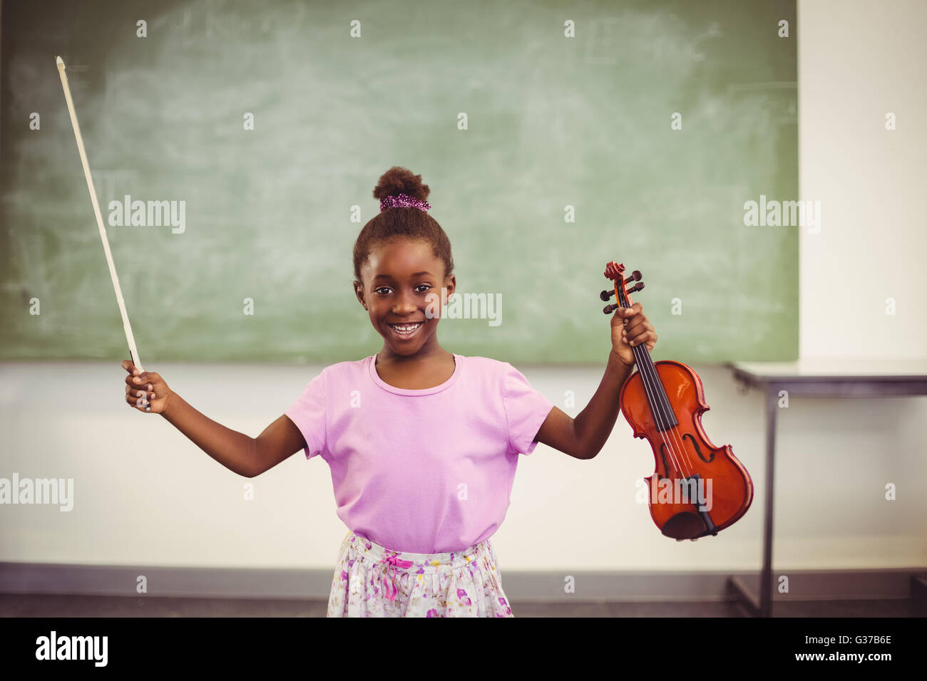 Portrait of smiling schoolgirl holding violin in classroom Stock Photo ...
