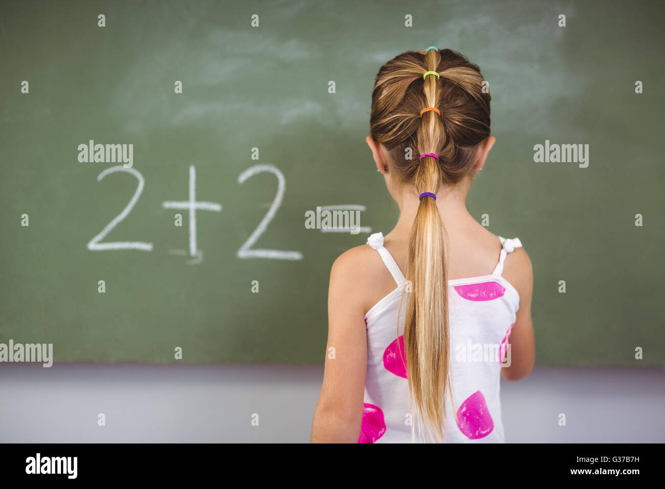 Schoolgirl doing mathematics on chalkboard in classroom Stock Photo