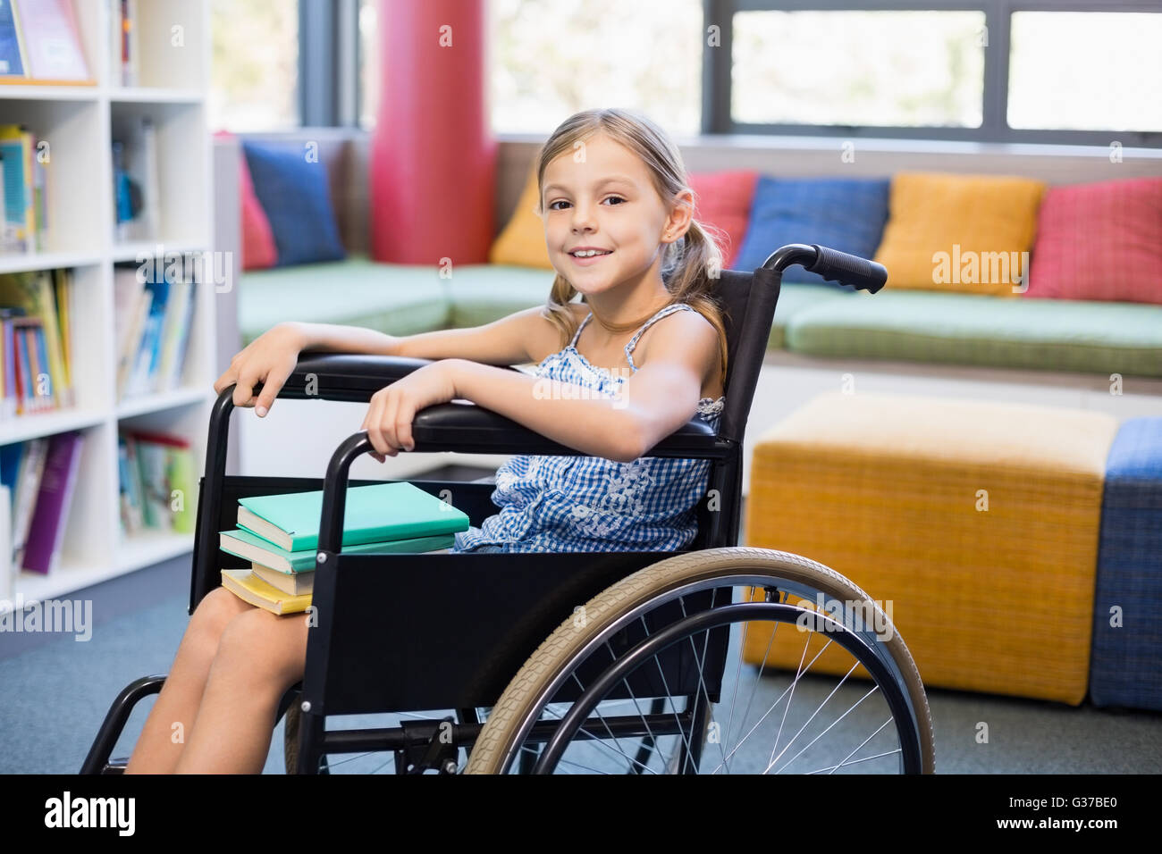 Disabled school girl with books in library Stock Photo