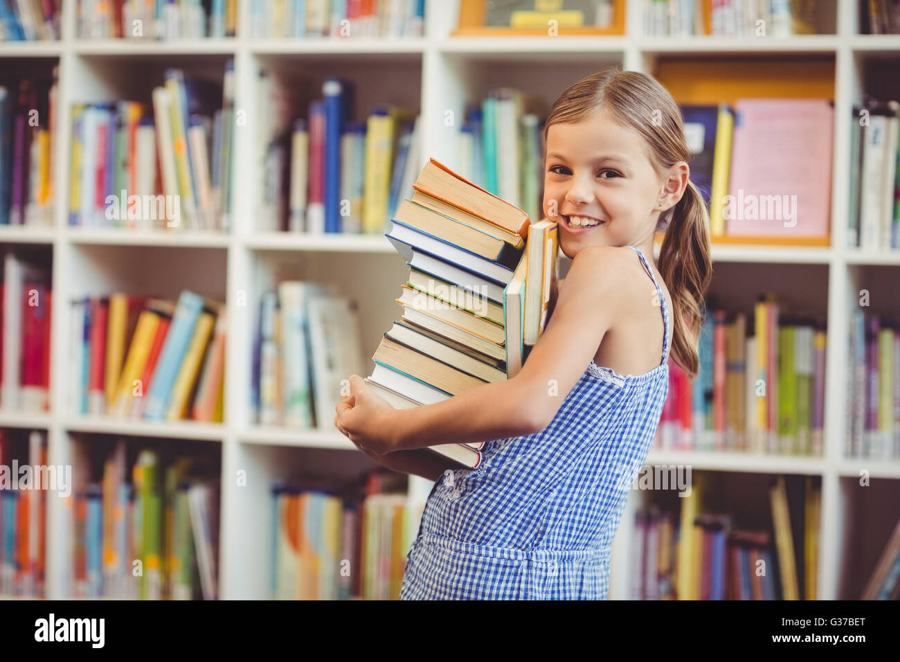 School girl holding stack of books in library Stock Photo - Alamy