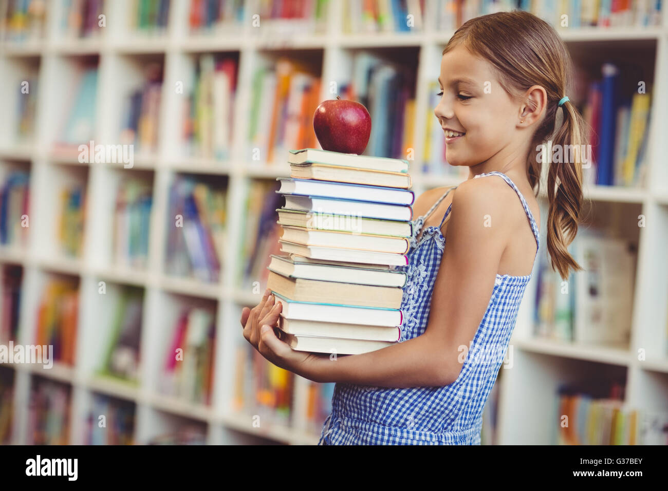 School girl holding stack of books in library Stock Photo - Alamy
