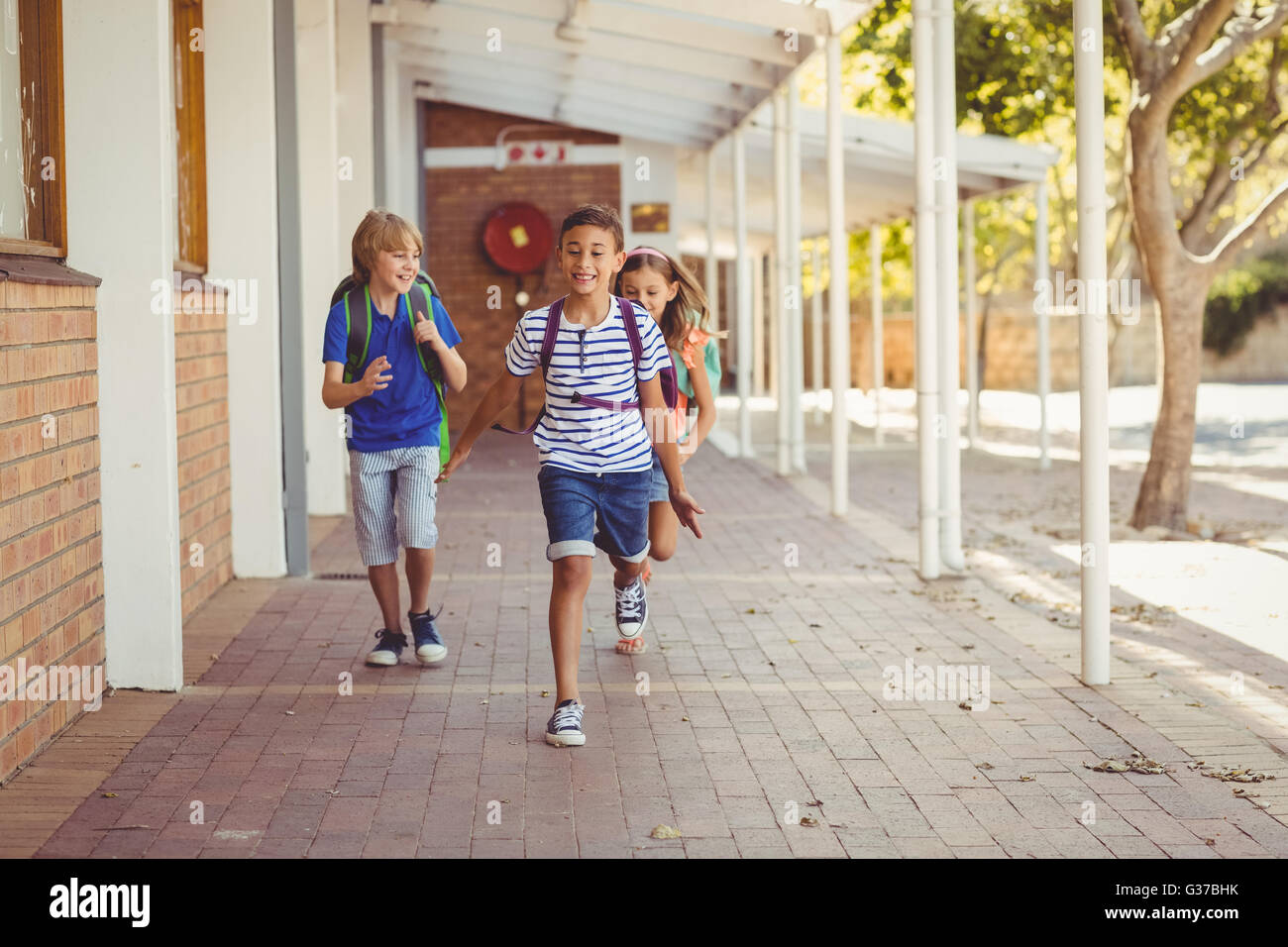 Happy school kids running in corridor Stock Photo