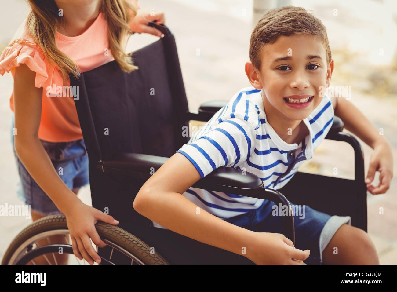 Happy schoolgirl pushing a boy on wheelchair Stock Photo - Alamy