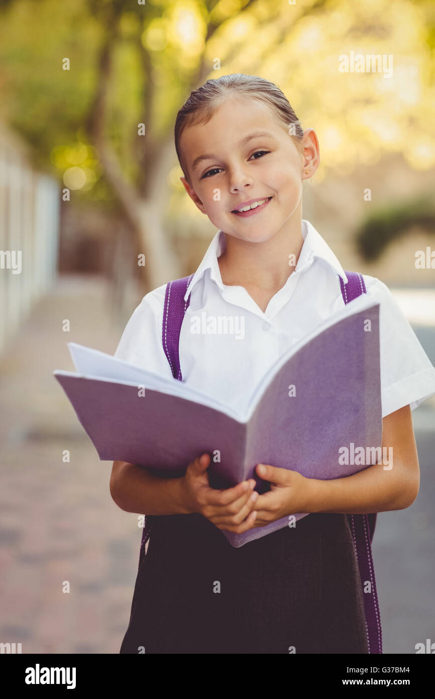 Happy schoolgirl reading book in campus Stock Photo - Alamy