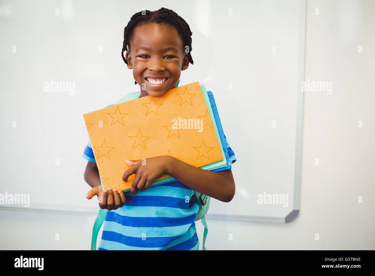 Happy schoolboy holding a book in classroom Stock Photo - Alamy