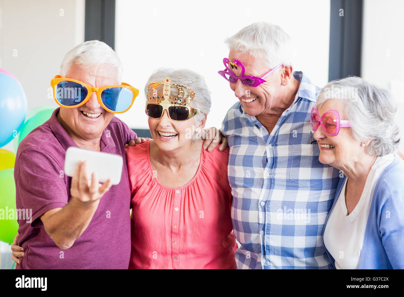 Seniors taking a selfie with funny glasses Stock Photo
