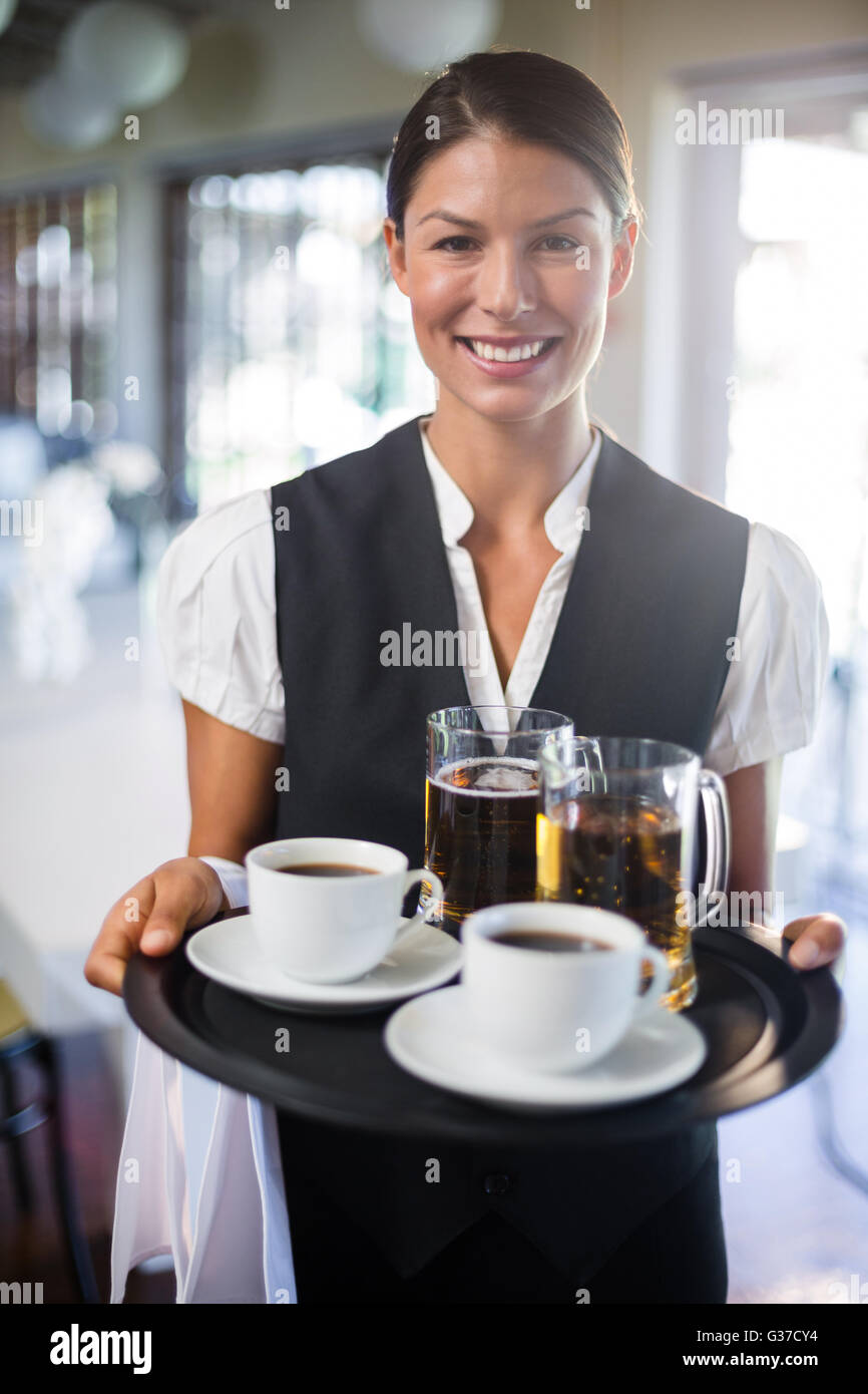 Waitress holding serving tray with coffee cup and pint of beer Stock Photo