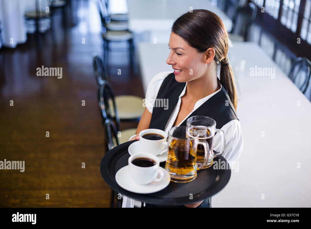 Waitress holding serving tray with coffee cup and pint of beer Stock Photo