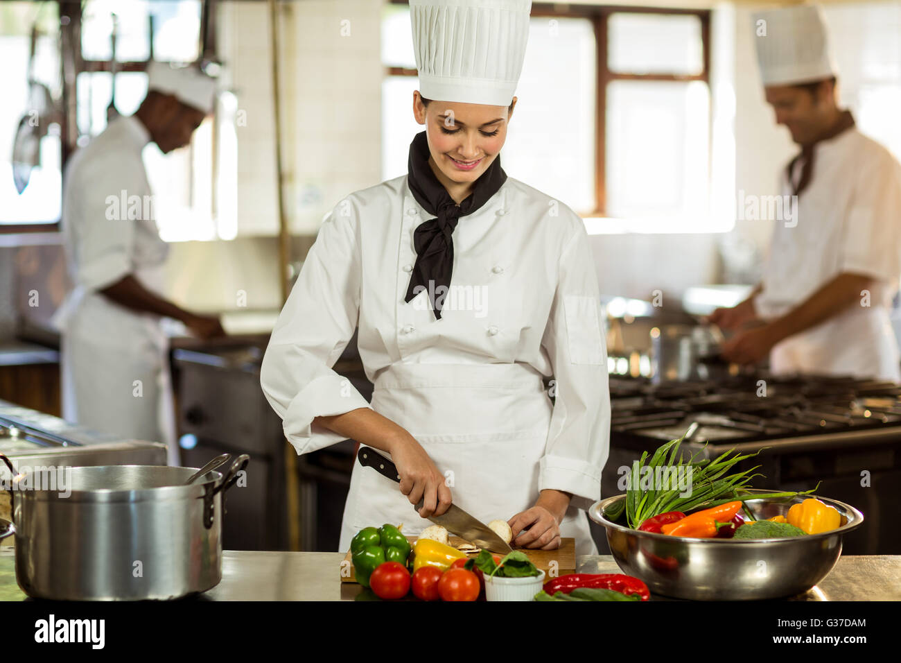 Young female chef cutting vegetables Stock Photo