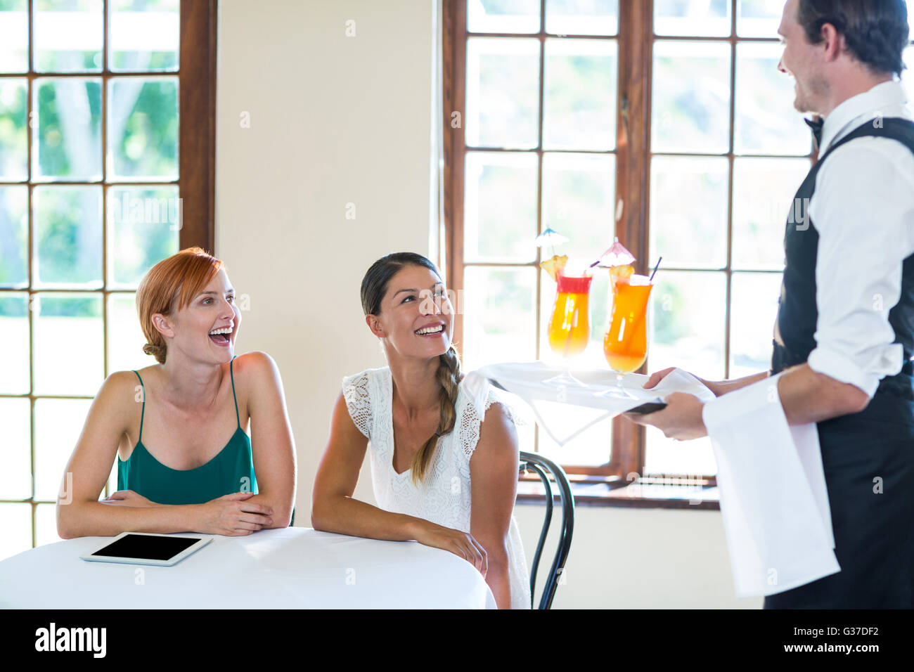 Waiter serving cocktail to women in restaurant Stock Photo Alamy