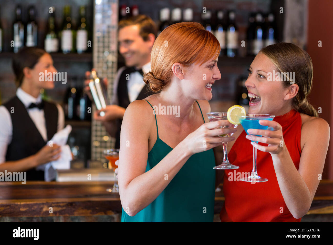 Friends holding a cocktail in front of bar counter Stock Photo