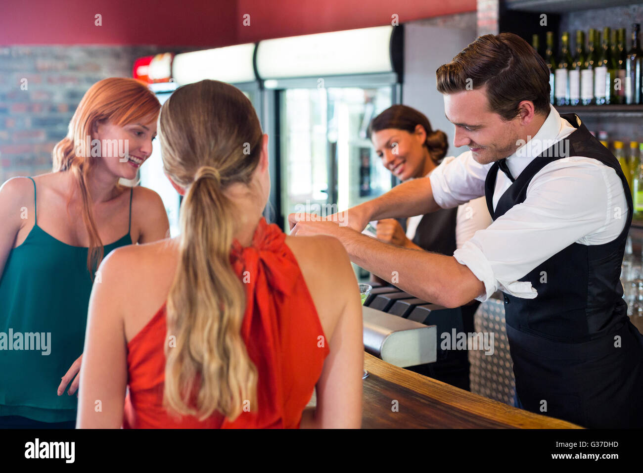 Friends standing at counter while bartender preparing a drink Stock Photo