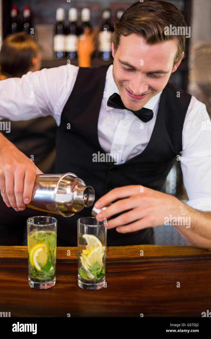 Bartender pouring a drink from a shaker to a glass on bar counter Stock  Photo - Alamy