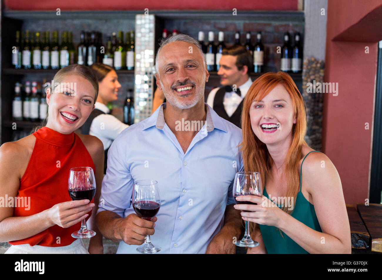 Portrait of friends standing at bar counter with a glass of red wine Stock Photo