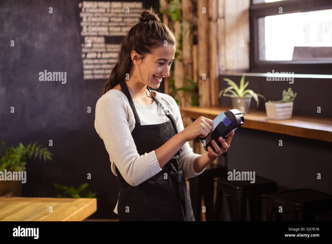 Smiling waitress using a bank card reader Stock Photo