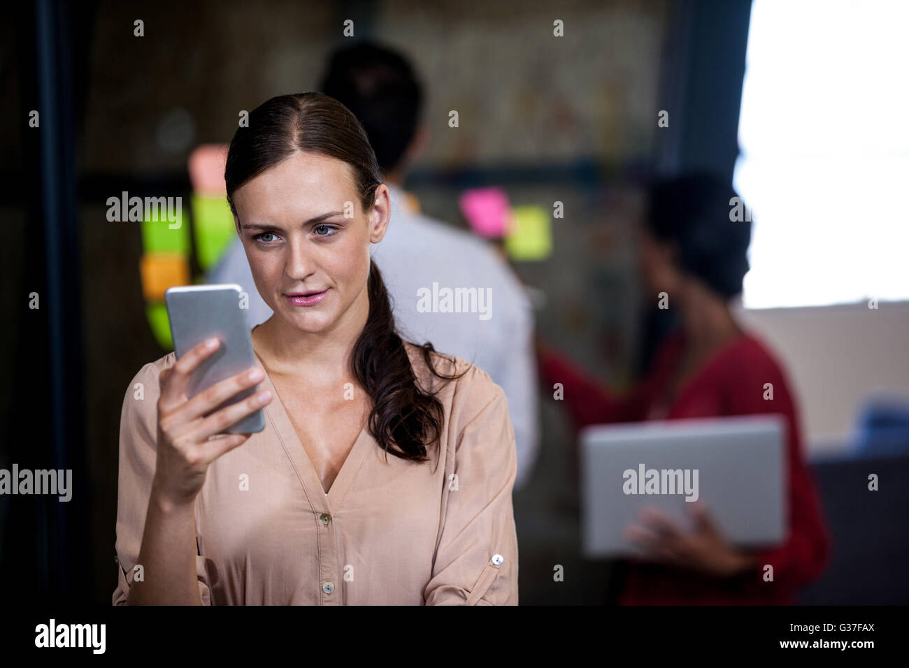 Focus on foreground of woman looking her mobile phone Stock Photo