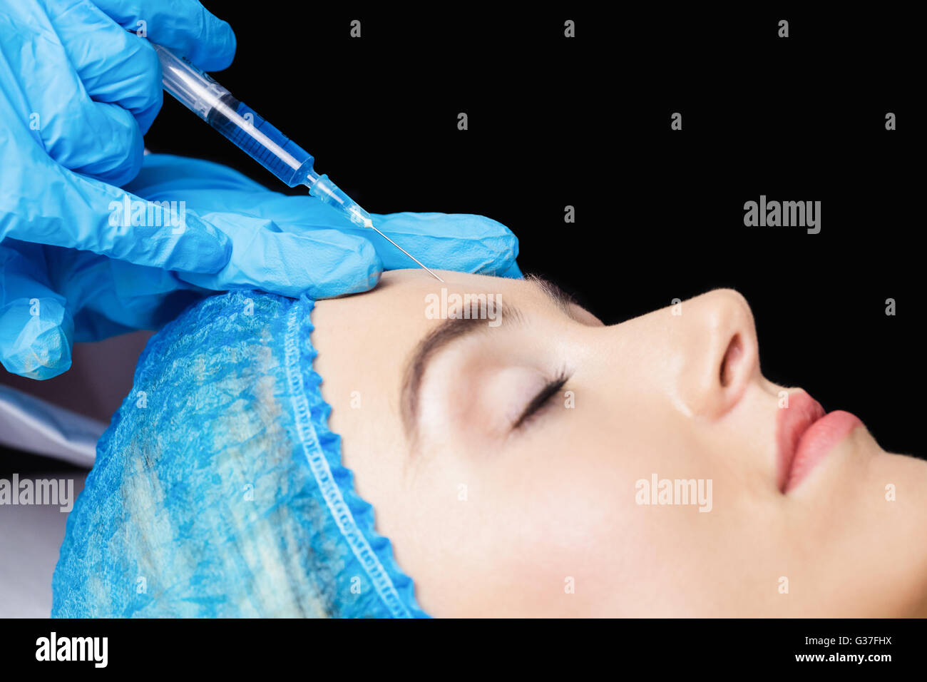 Woman receiving botox injection on her forehead Stock Photo