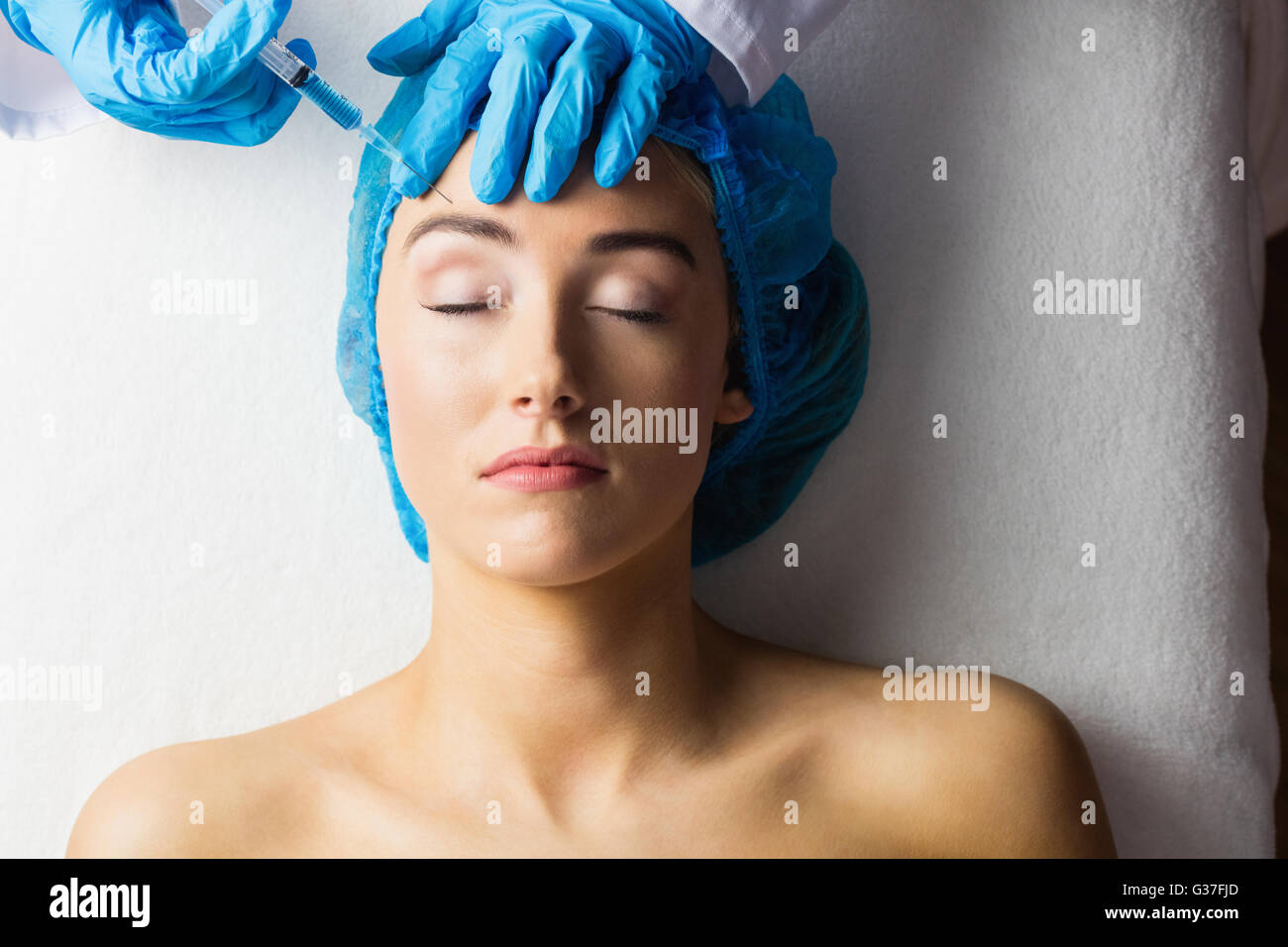 Woman receiving botox injection on her forehead Stock Photo