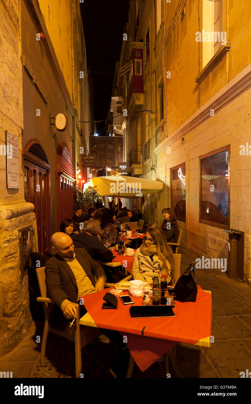 Bars and cafes set tables in the alley known as Strait Street in Valletta in the evenings. Stock Photo