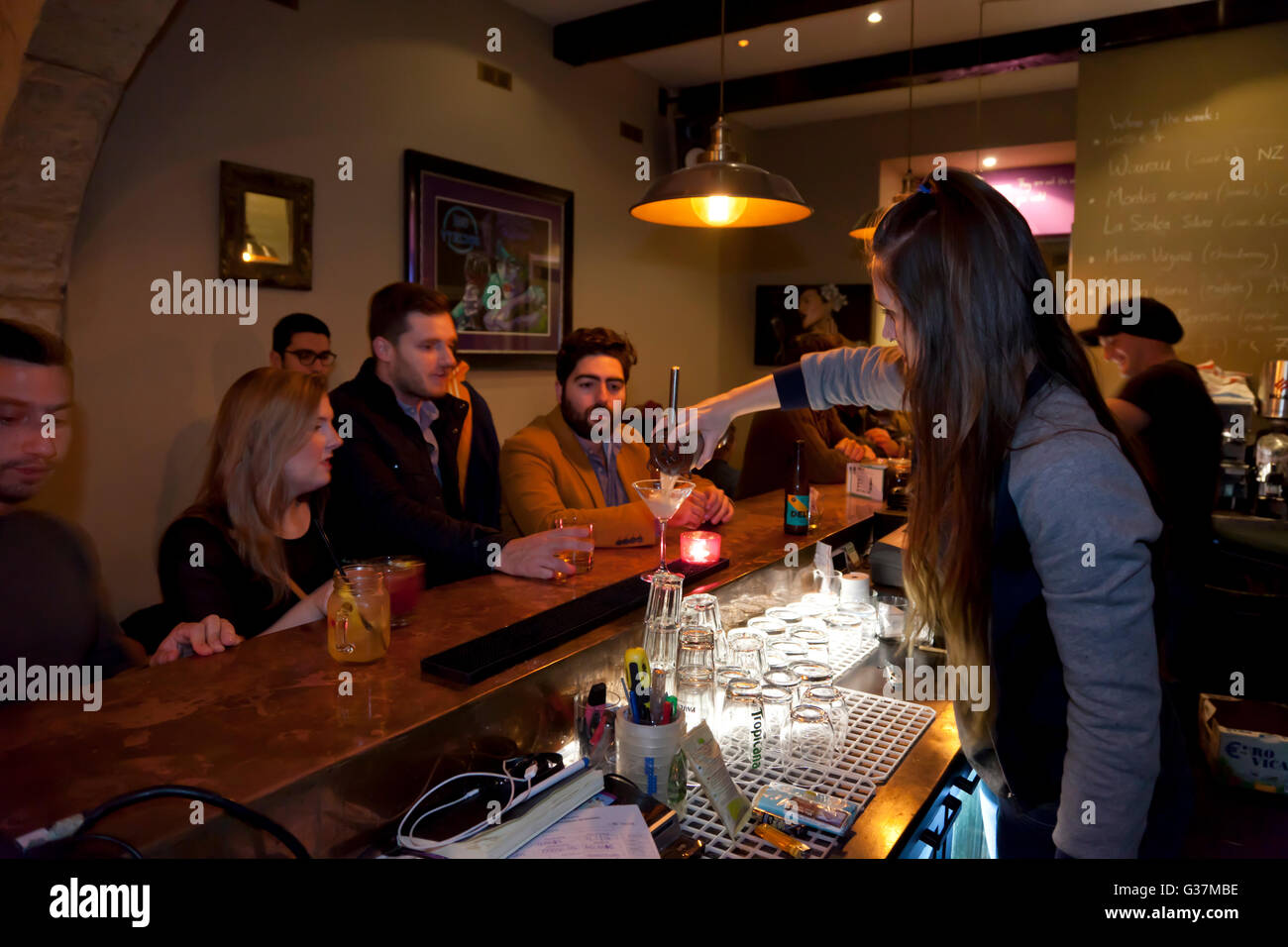 Customers watch a bartender make a cocktail at a bar in Valletta Stock