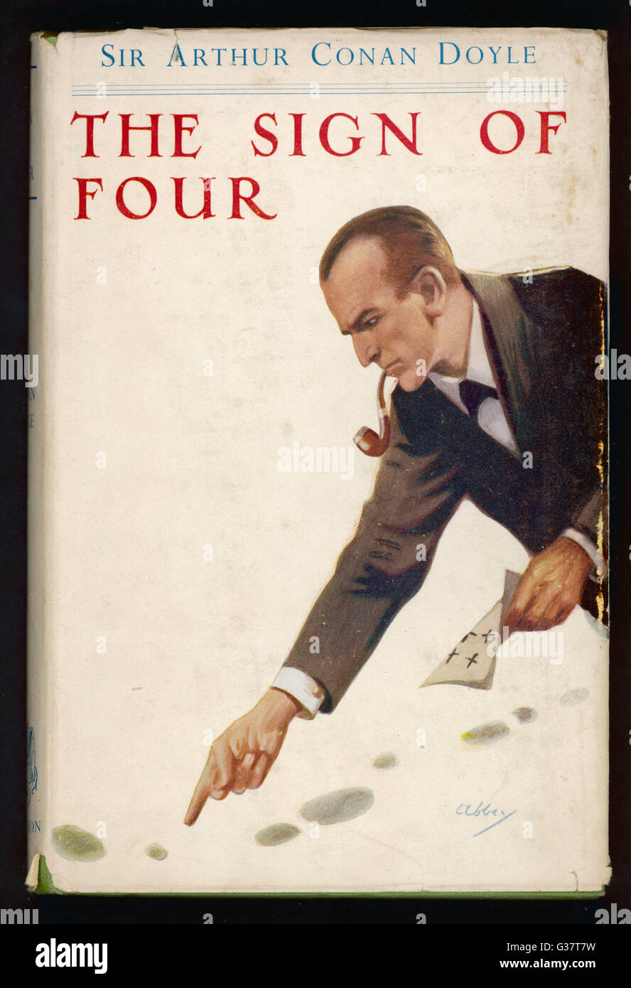 THE SIGN OF FOUR  Holmes, pipe between his  teeth, examines footprints.       Date: First published: 1890 Stock Photo