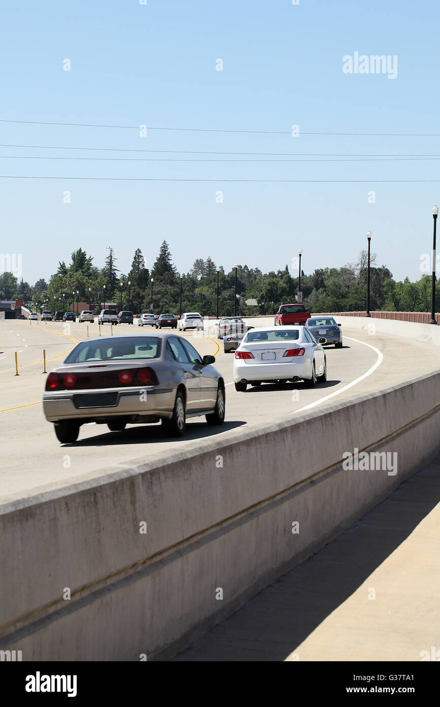 cars going around curve in the road away from viewer Stock Photo