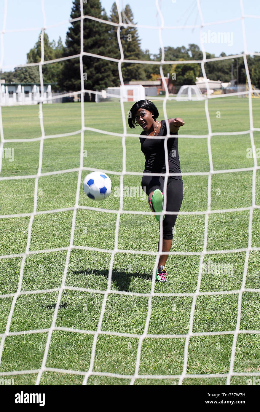 Young African American woman kicking soccer ball goal Stock Photo - Alamy